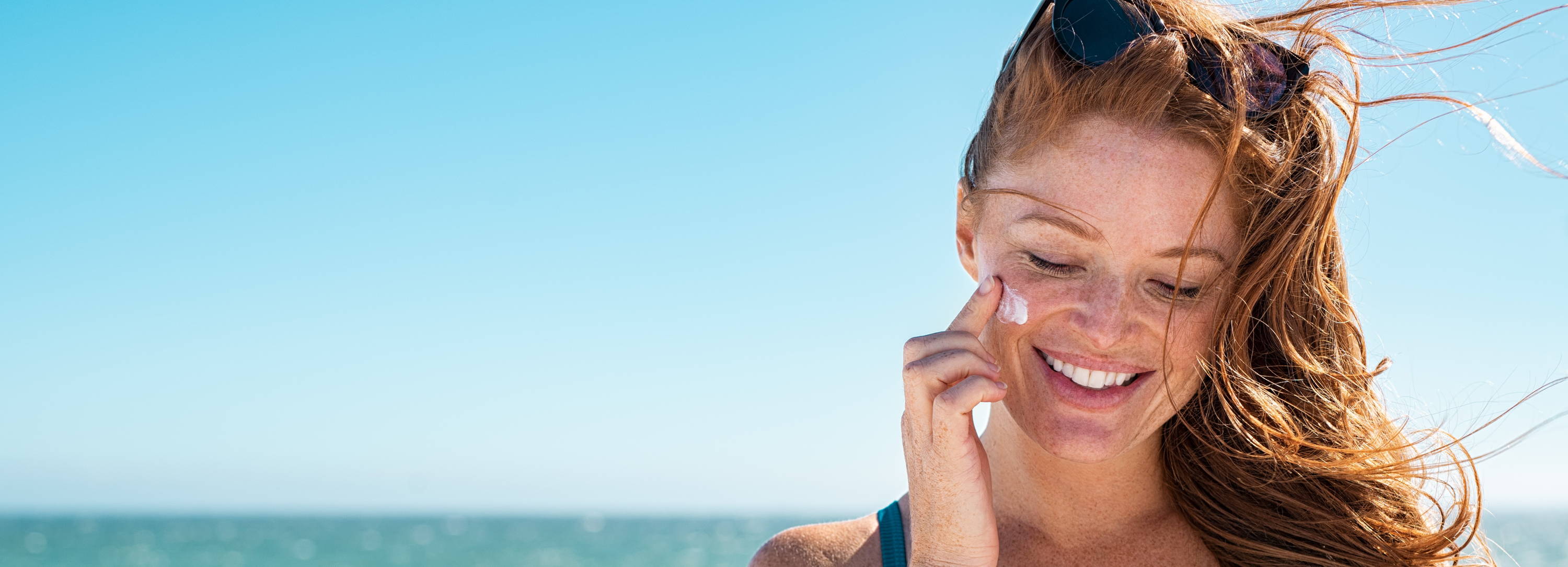 Woman applies sunscreen to her cheek