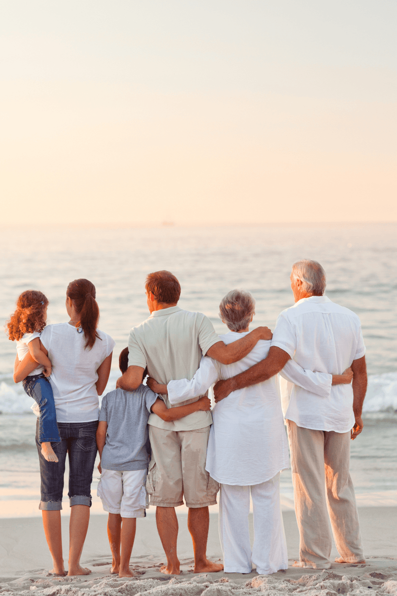 A happy family at the beach facing the water.