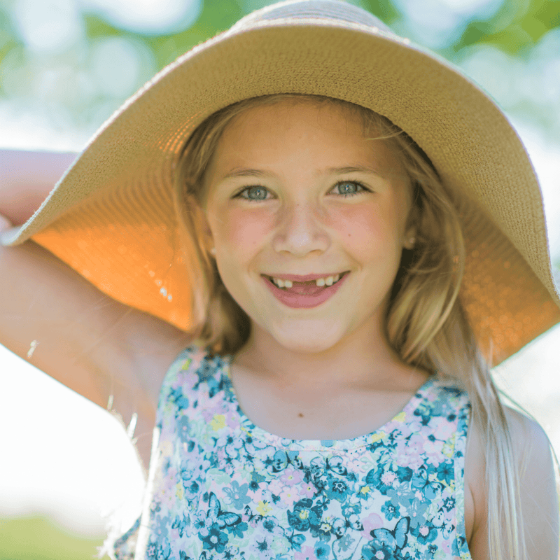 Young girl wearing a wide-brimmed hat with a blurred natural background