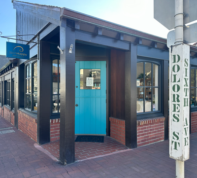 The SkinHappy Building with a blue door on a street corner, featuring a sign for 'Sixth Street and Dolores'.