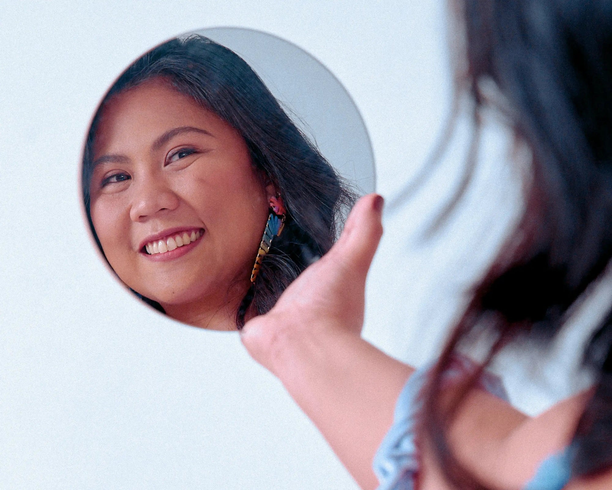 Reflection of a smiling person in a round mirror.