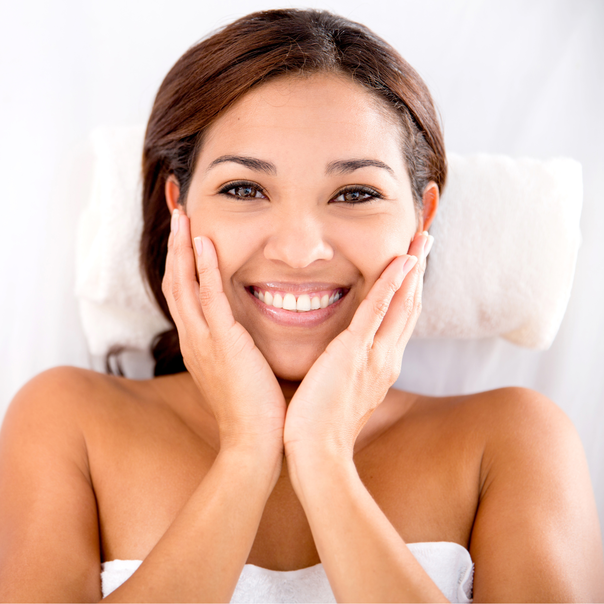 Woman with a radiant smile and hands on face against a white background