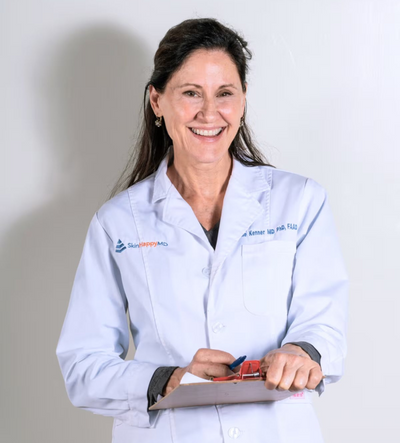 Dr Julie Kenner wearing a white lab coat, holding a clipboard against a plain background