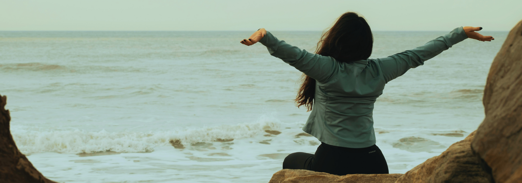 Person with arms outstretched on a beach