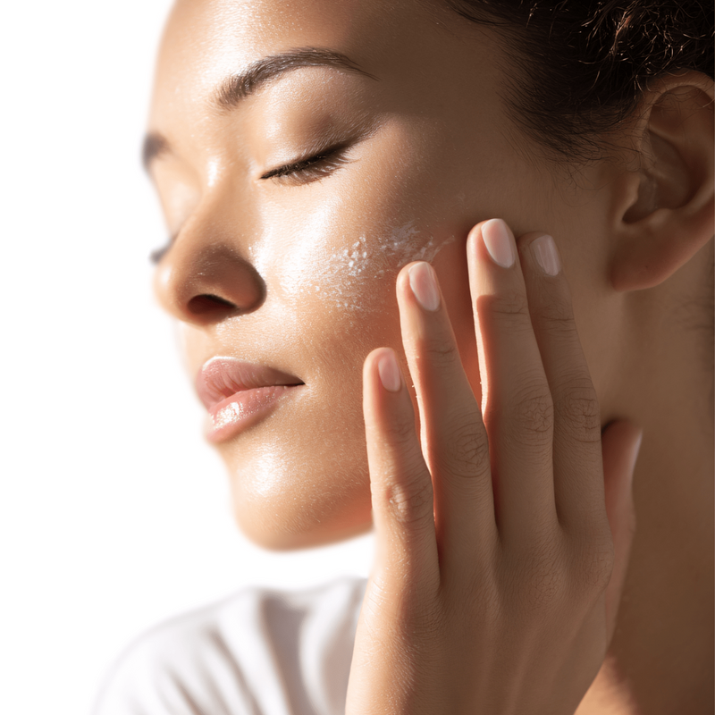 Woman applying a skincare product to her face with a white background