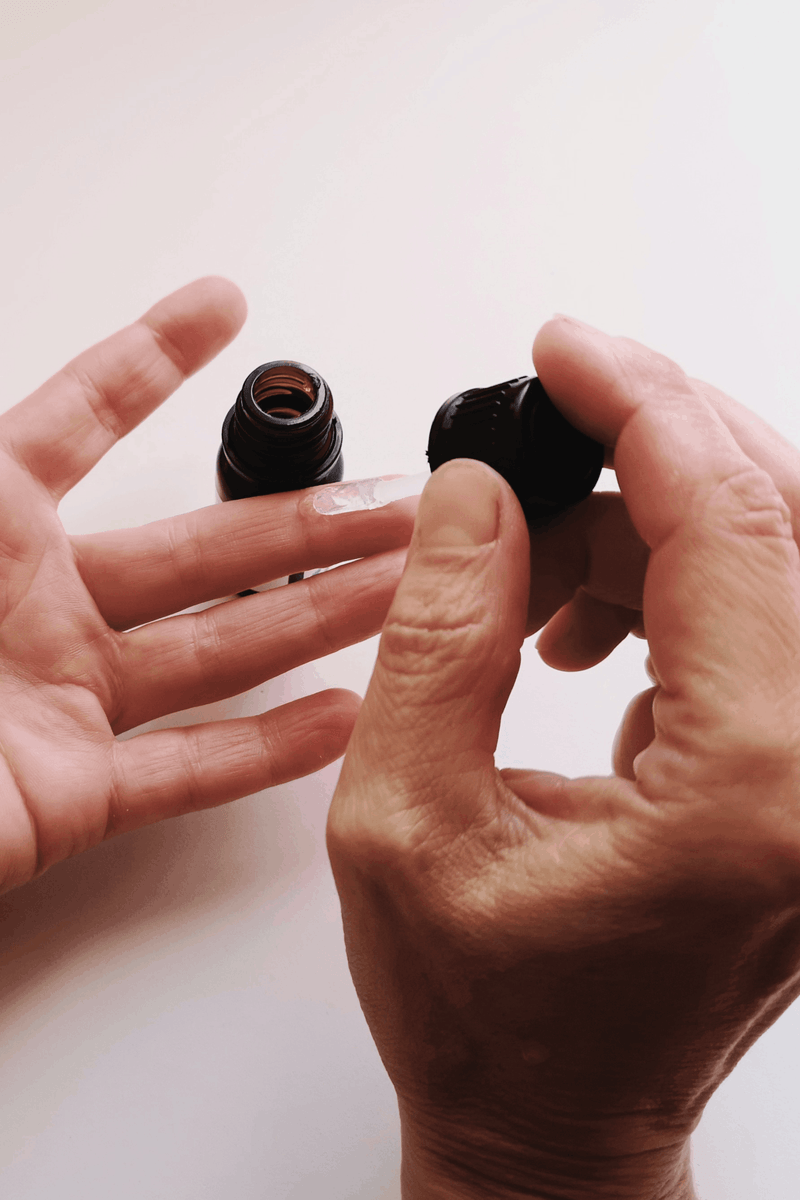 A person applies a medication to their finger. 